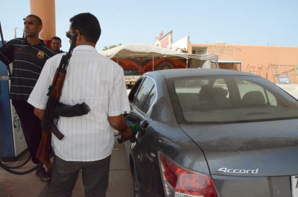 ガソリン不足に見舞われるリビア。GSの従業員は襲われないようにカラシニコフ銃を肩に給油する。(トリポリ―ミスラータ街道のGSで。筆者撮影)