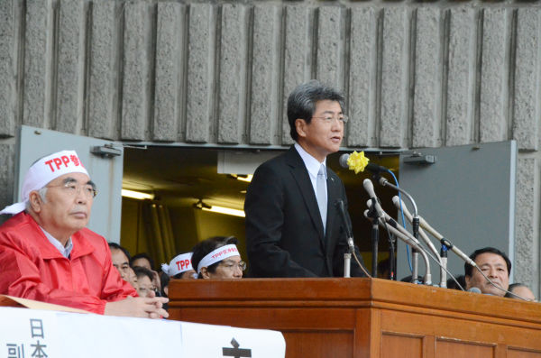 挨拶する中川俊男・日本医師会副会長。「TPPは日本の医療に深刻な影響を及ぼす」。左（赤ジャンパー）はJA全中の萬歳章会長。＝26日、日比谷野音。写真：筆者撮影＝
