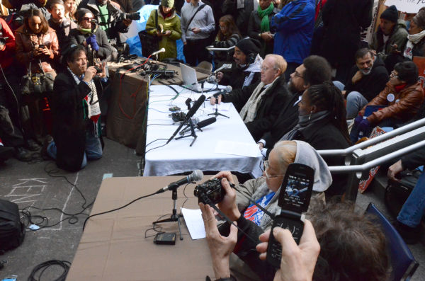 市民集会で「Occupy(占拠)行動」を鼓舞するクリス・ヘッジズ記者（テーブル席の奥から2番目）。＝同日、ズコッティ・パーク。写真：筆者撮影=
