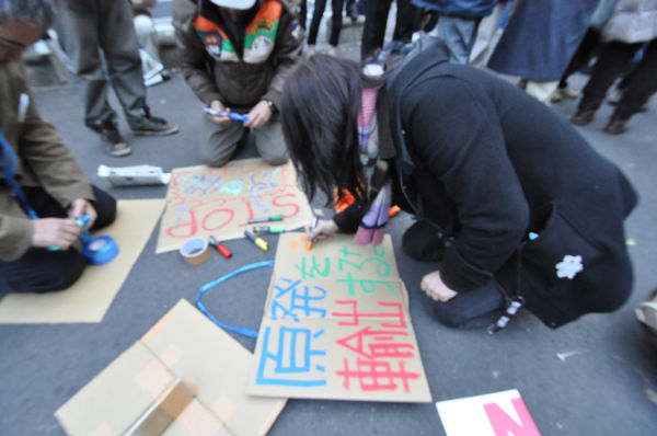 女性はデモ集合場所にマーカーとダンボールを持ち込み「原発を輸出するな」と書いた。＝日比谷公園。写真：筆者撮影＝