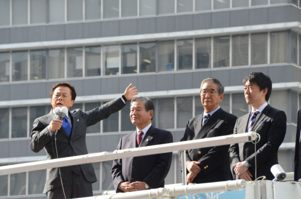 猪瀬直樹候補（左端）は、石原前知事と橋下大阪市長らに見守られながら第一声をあげた。＝29日午前11時頃、新宿西口。写真：田中撮影＝